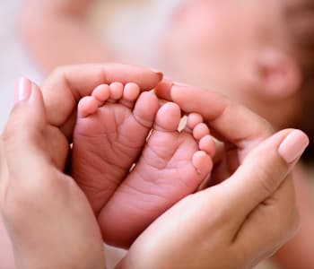 maman tenant les pieds de son bébé entre ses mains