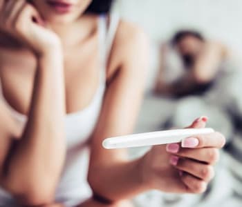 Femme inquiète qui regarde un test de grossesse sur son lit