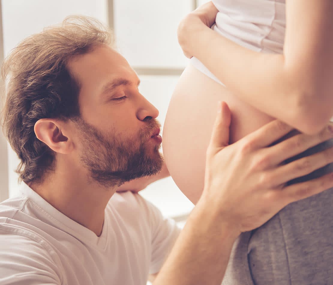 homme embrassant le ventre de sa femme enceinte