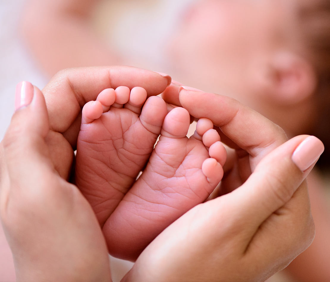 maman tenant les pieds de son bébé entre ses mains