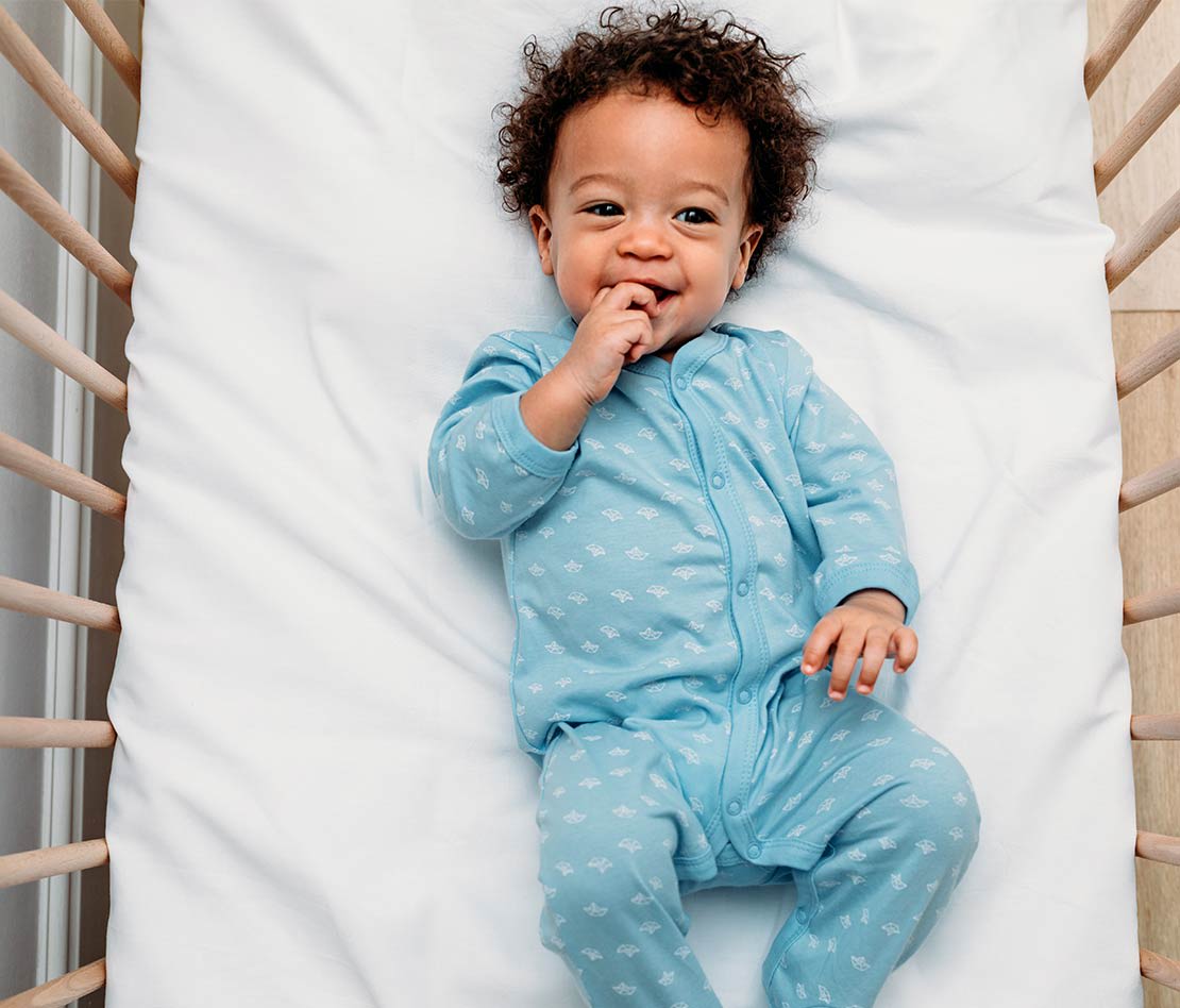 bébé portant un pyjama ou une grenouillère dans son lit avant de dormir