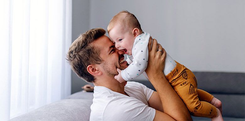 Homme heureux qui porte un bébé dans les bras