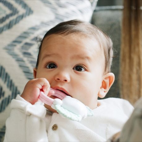 bebe avec un jouet a la bouche