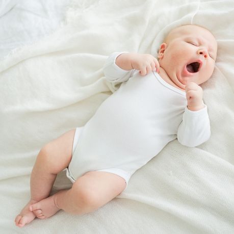 bebe baille et en body allonge sur le lit