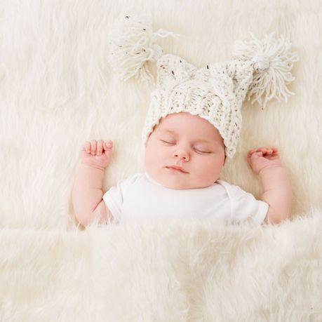 bebe allonge les bras en l air avec un bonnet