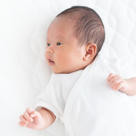 bebe habille en blanc et allonge sur un lit