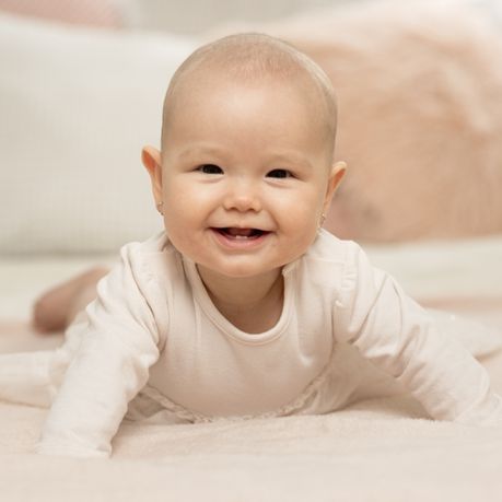 bebe qui sourit sur le ventre
