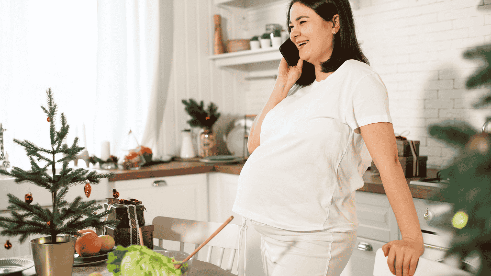 Femme enceinte au téléphone dans la cuisine à Noël