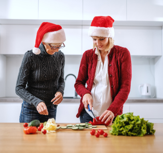 Photo d'une maman et de sa fille adulte qui cuisinent avec un bonnet de Noël