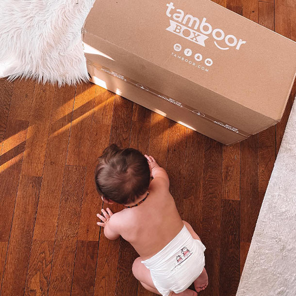 bébé rampant sur du parquet, avec couche tamboor et box de couches tamboor by orchestra