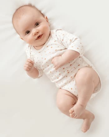 bebe en body allonge sur un lit