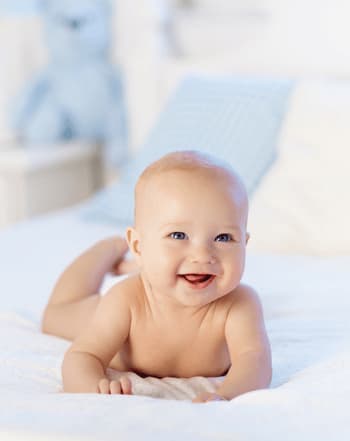 bebe souriant nu allonge sur le ventre