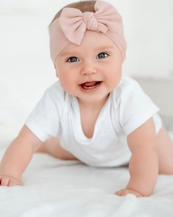 bebe fille a quatre pattes avec un noeud sur la tete