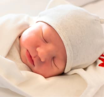 bébé qui dort avec un bonnet blanc