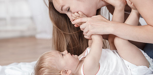 Maman faisant un bisou sur le pied de bébé