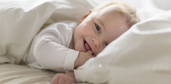 bébé souriant les doigts dans la bouche
