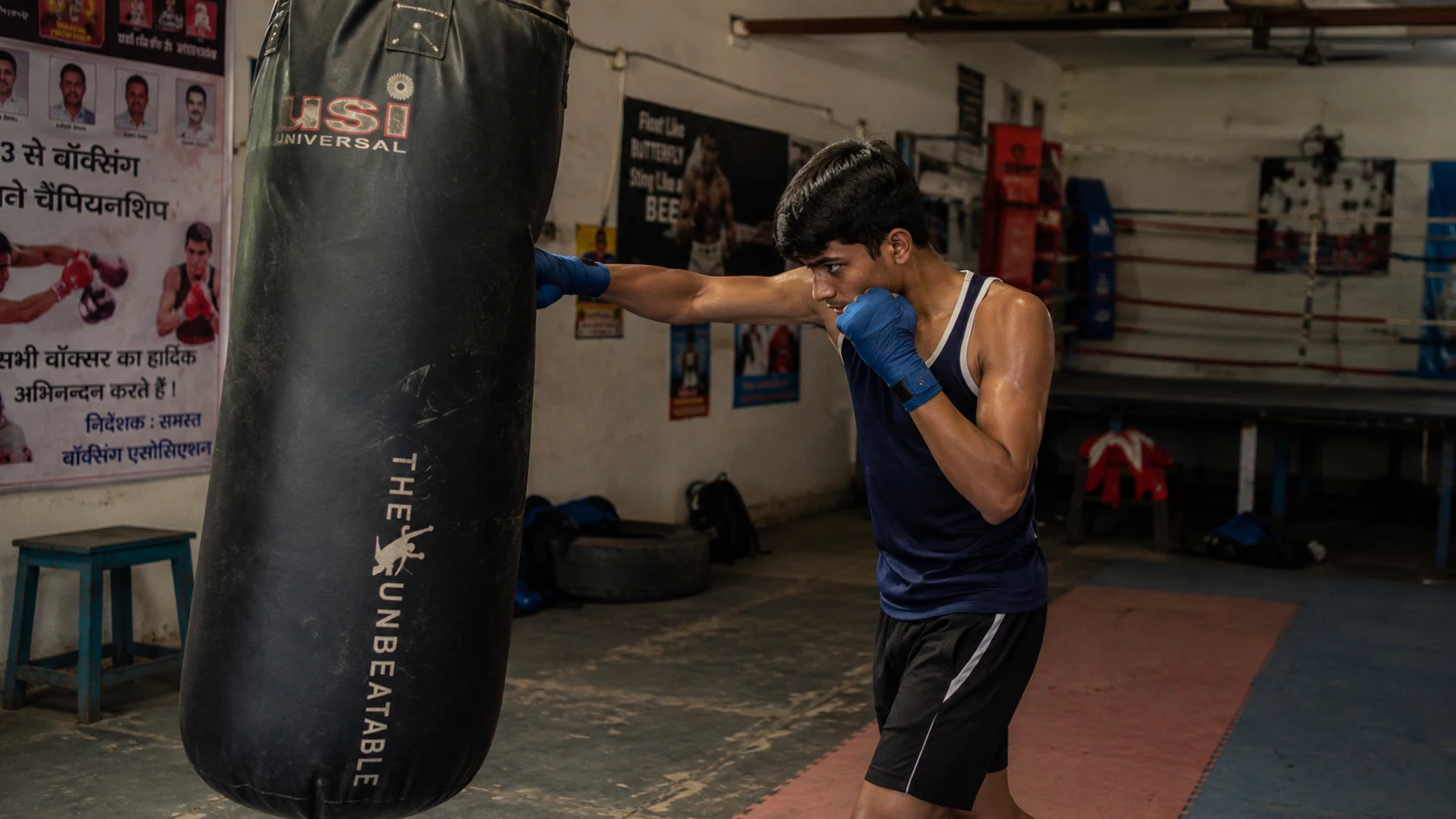 Teen boxer training on a heavy bag in an Indian gym