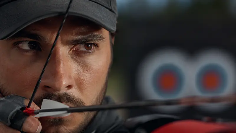 Close-up of archer's focused eye on the target at full draw