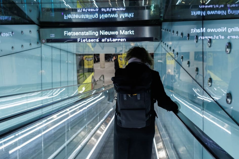 a person with a backpack is going down an escalator