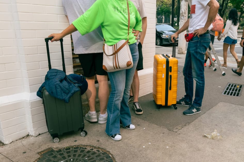 A group of people standing on a sidewalk with luggage