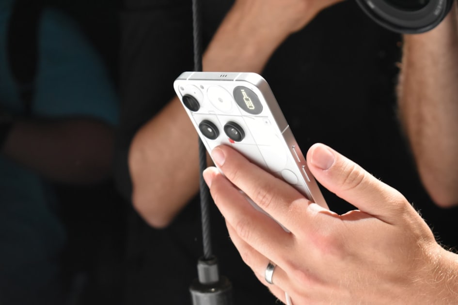 Person holding a white smartphone with a camera lens