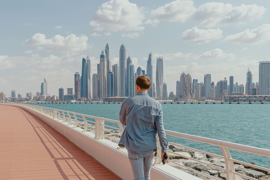A man walking on a bridge with a city in the background