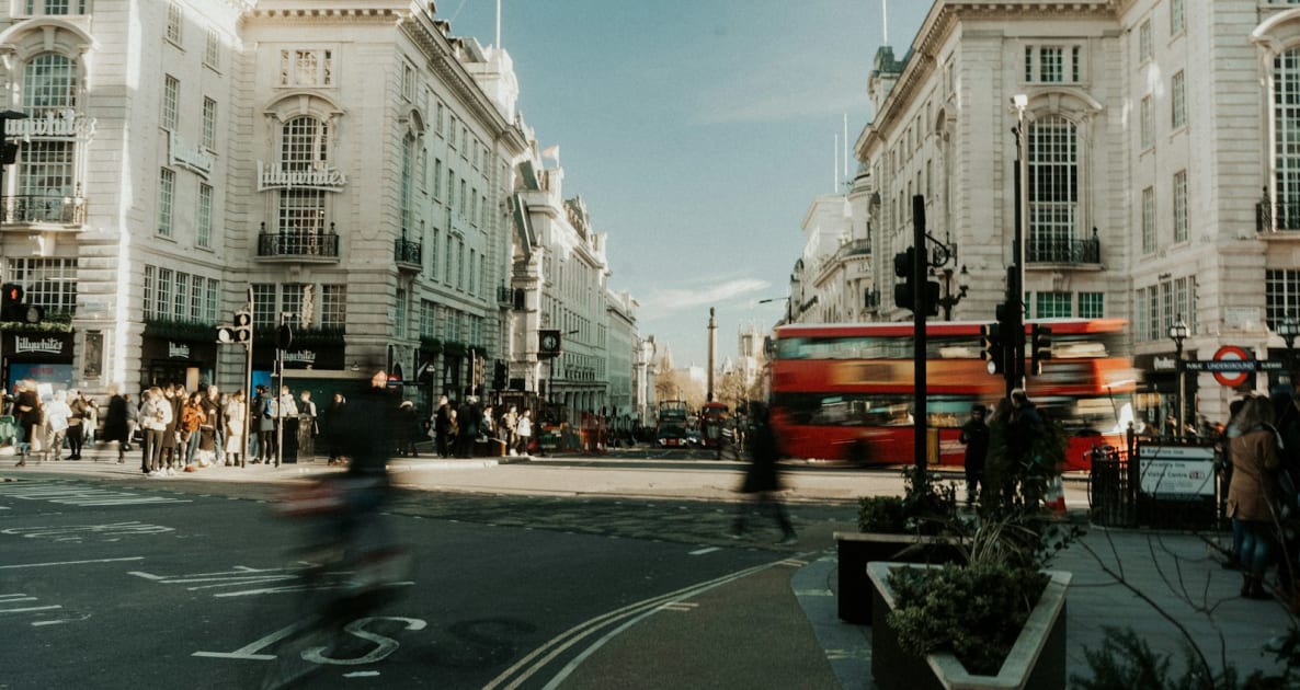 A red double decker bus driving down a street
