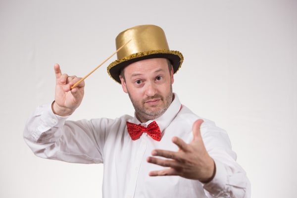 Ritratto giocoso di Daniele Camiz con cilindro dorato, papillon rosso e bacchetta in mano.