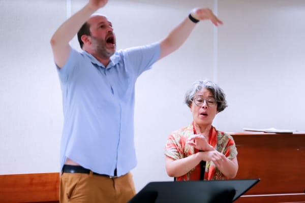 Daniele Camiz dirige con gesto ampio accanto alla solista durante una prova.