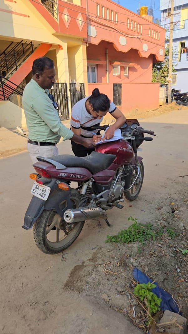 Customer signing documents before Bajaj Pulsar bike scrapping in KR Puram Bangalore by CarBasket - RC cancellation and legal scrap process