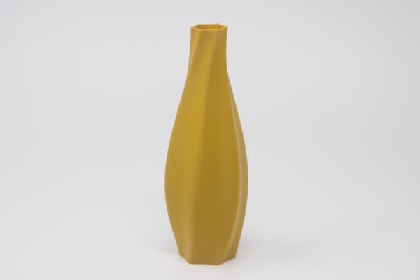 Twisting ochre colored vase on a white background.