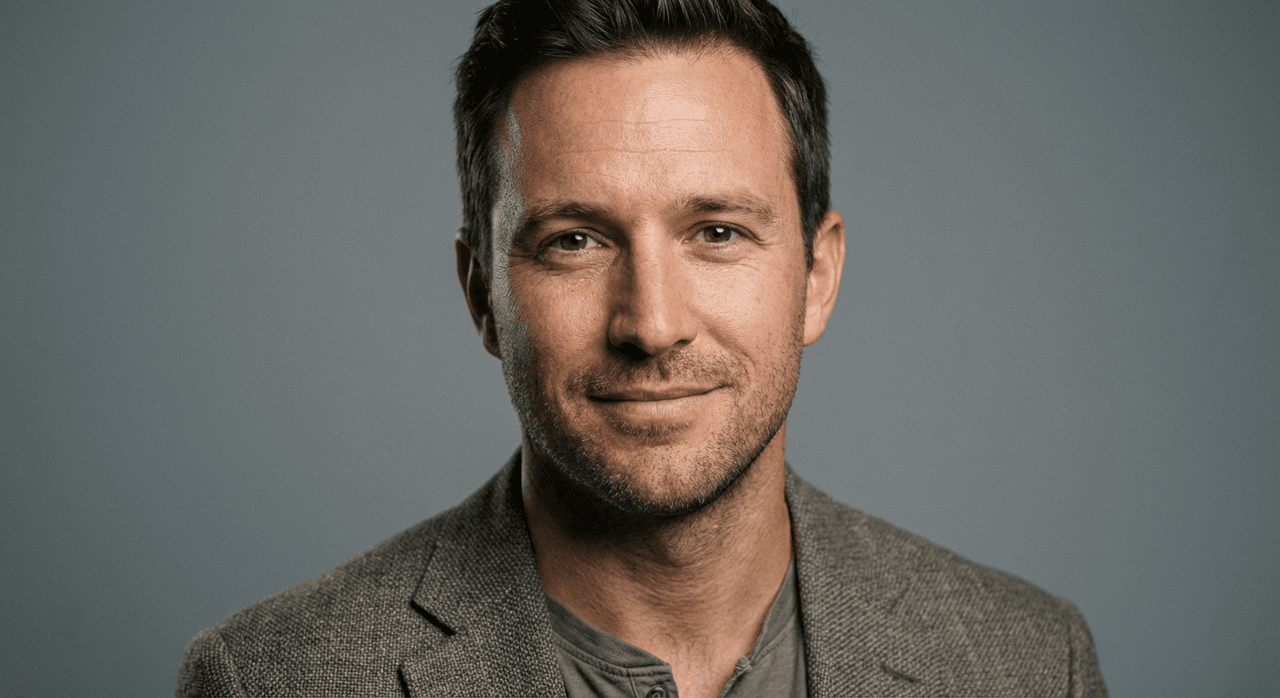 Professional headshot of confident man in gray blazer against neutral background, 2025
