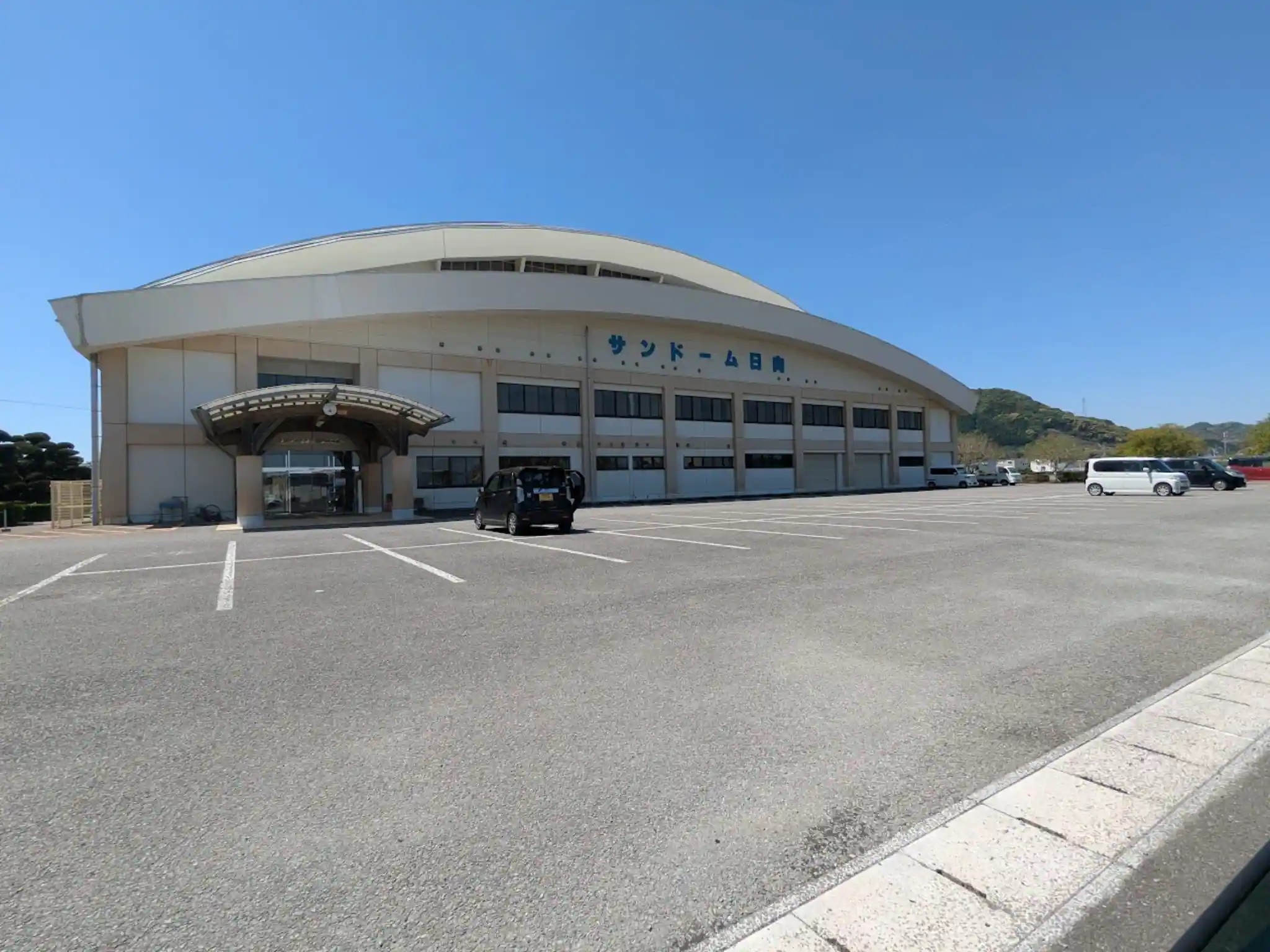 日向市お倉ヶ浜総合公園にあるサンドーム日向の外観と駐車場の様子