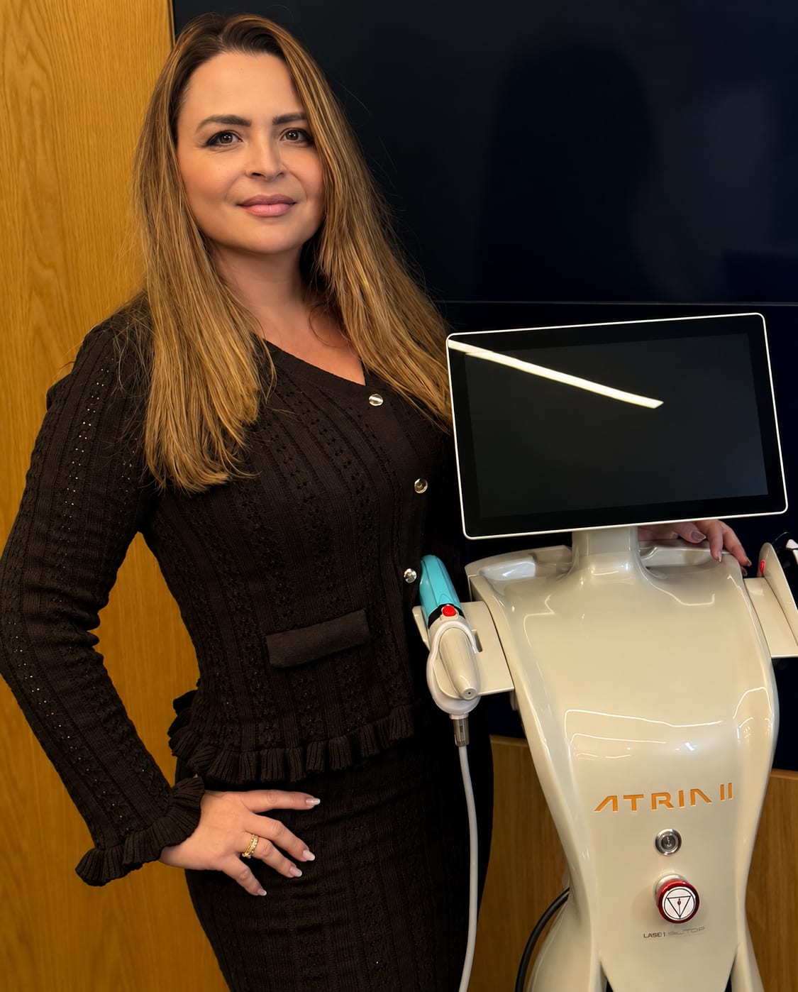 Dra. Daniele Murga ao lado de equipamento de laser da cl&iacute;nica