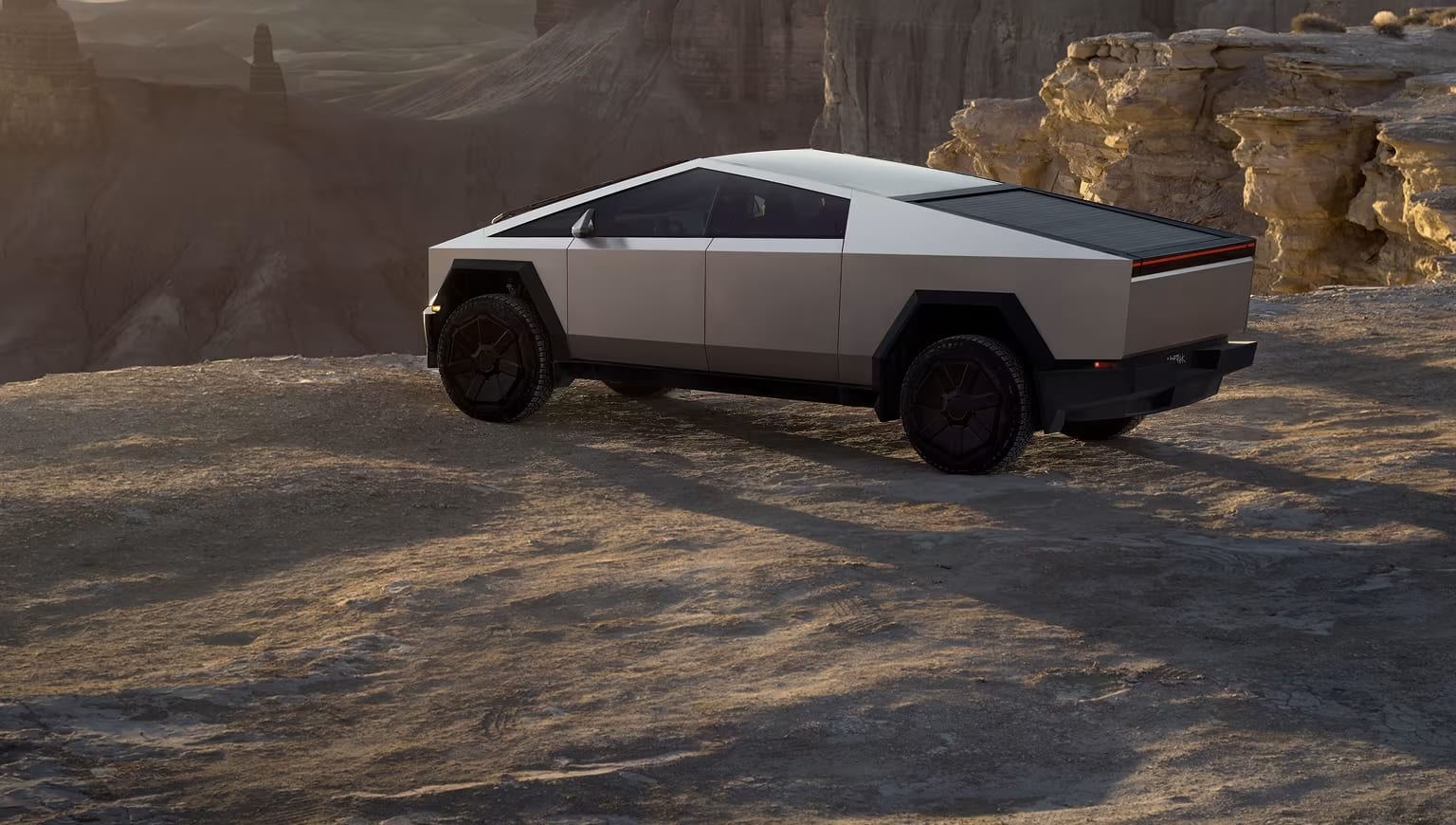 Cybertruck driving off-road in a desert landscape with mountains in the background