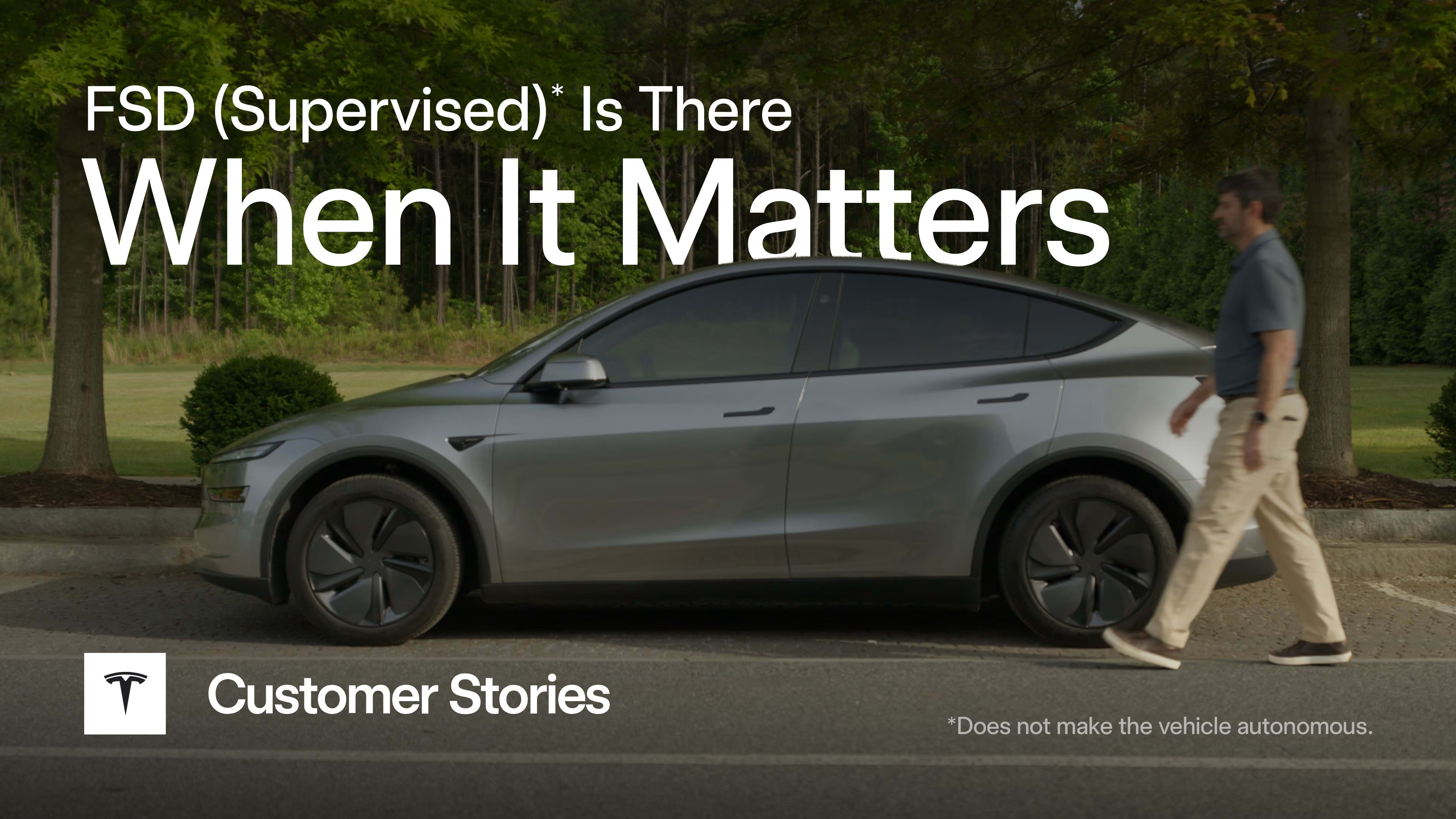 A silver Tesla Model Y parked on a roadside with a pedestrian walking nearby