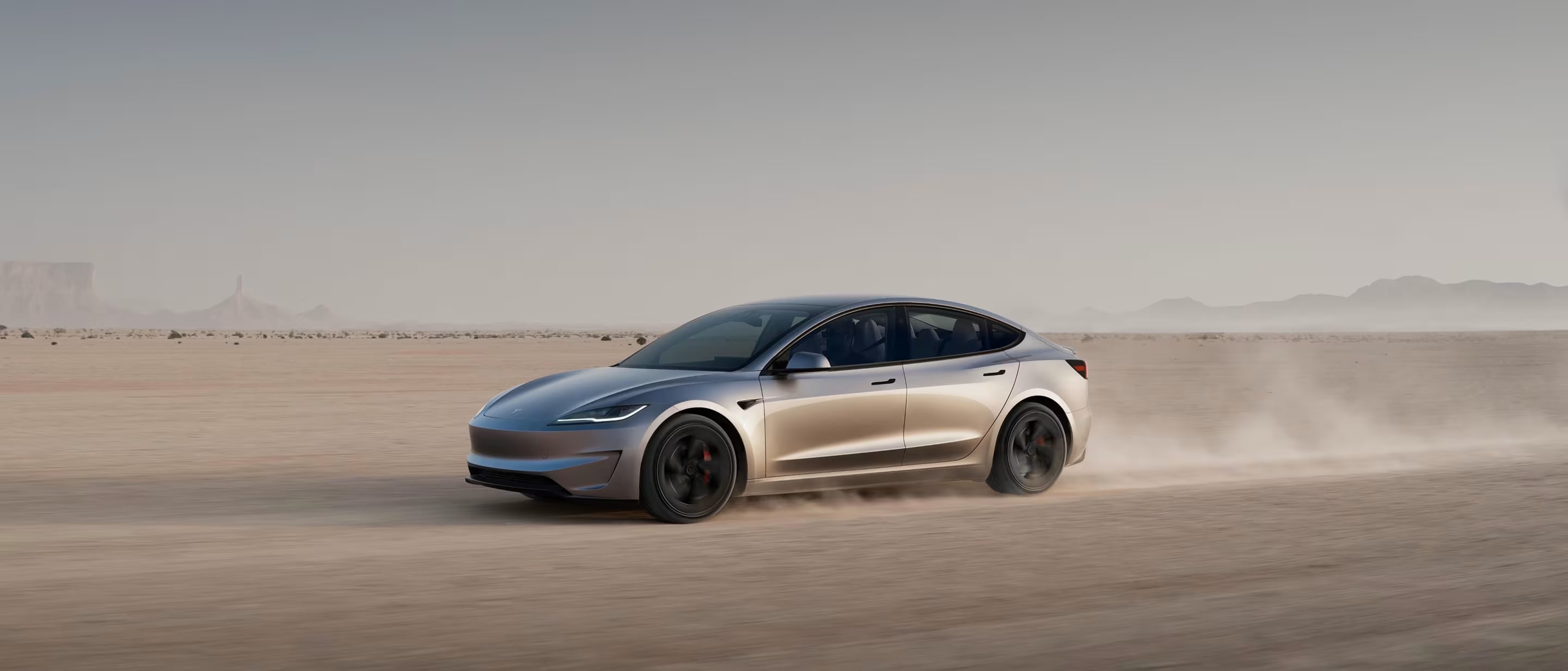 Red Model 3 driving on mountainous road
