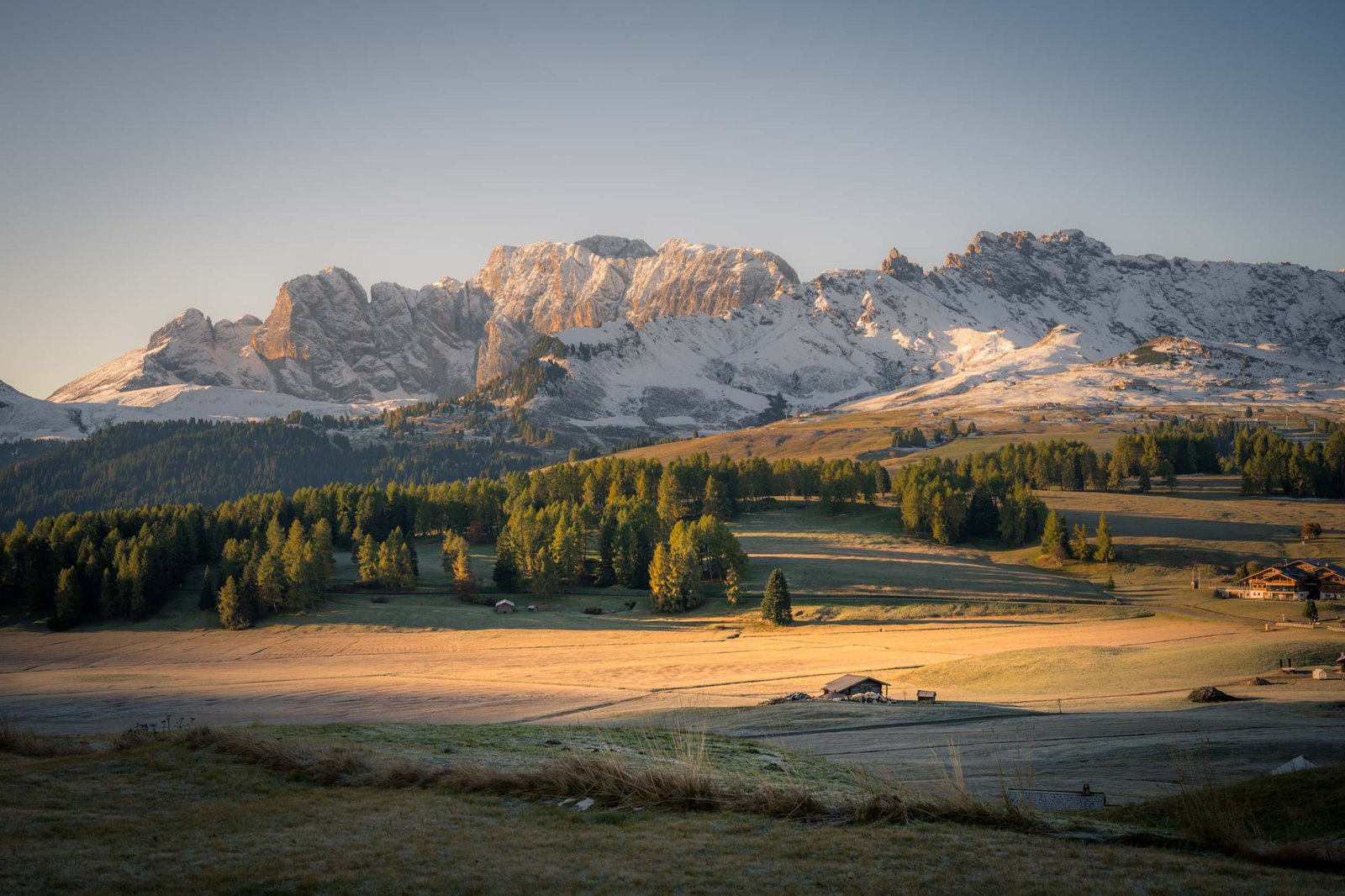 Seiser Alm bij zonsopkomst met ochtendnevel over de alpenweiden en Sassolungo op de achtergrond