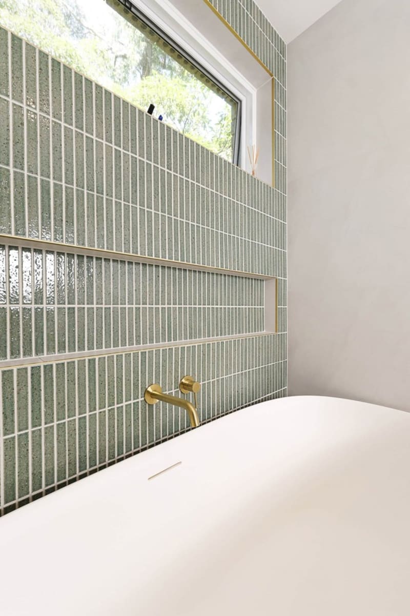 Kazoku Hatsu Border hand-glazed Japanese mosaic used as a slim feature band on a bathroom wall.