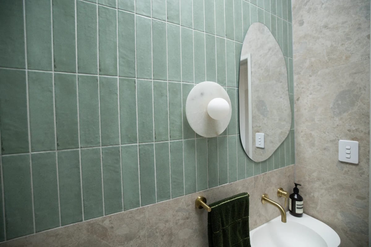 Powder room - the customer's green Zellige vertical-stacked across the upper walls, Norrock Ivory below, brushed brass and marble as the soft accents.