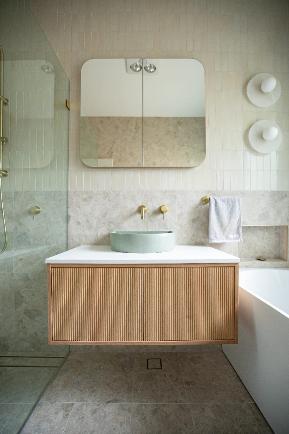 Vanity wide - Norrock Ivory wrapping the lower walls and floor, fluted timber drawers and brushed brass tapware reading against it.
