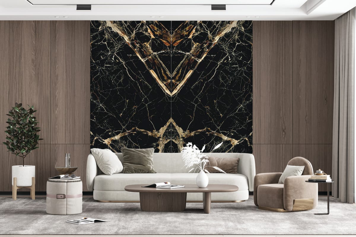 A book-matched Caravaggio Gold porcelain mega slab feature wall in a living room, the black and gold veining mirrored into a dramatic symmetrical pattern.