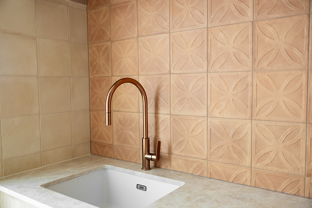 Amuri by Ragno handmade-look Italian porcelain terracotta tile styled in a Sydney interior, marked edges and soft surface clouding that echo handmade clay.