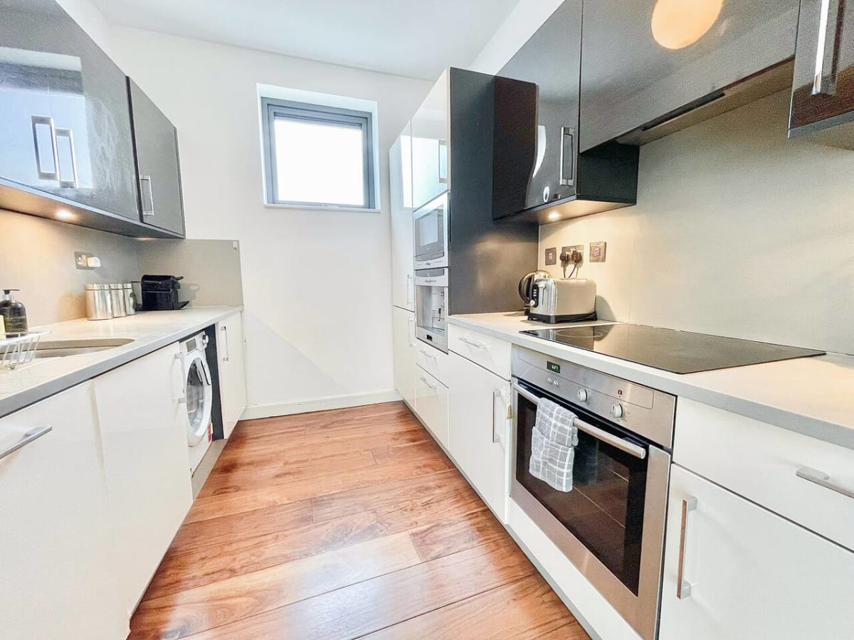 Galley kitchen with white units and a window at the Pentonville Road apartment