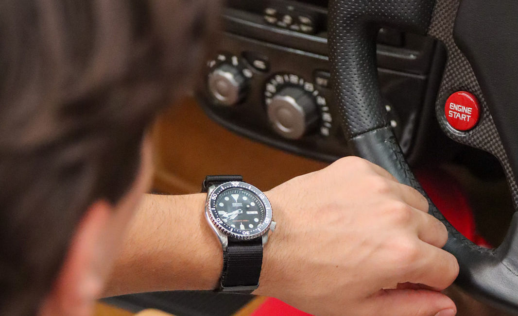 Wrist wearing a Seiko dive watch on a black NATO strap