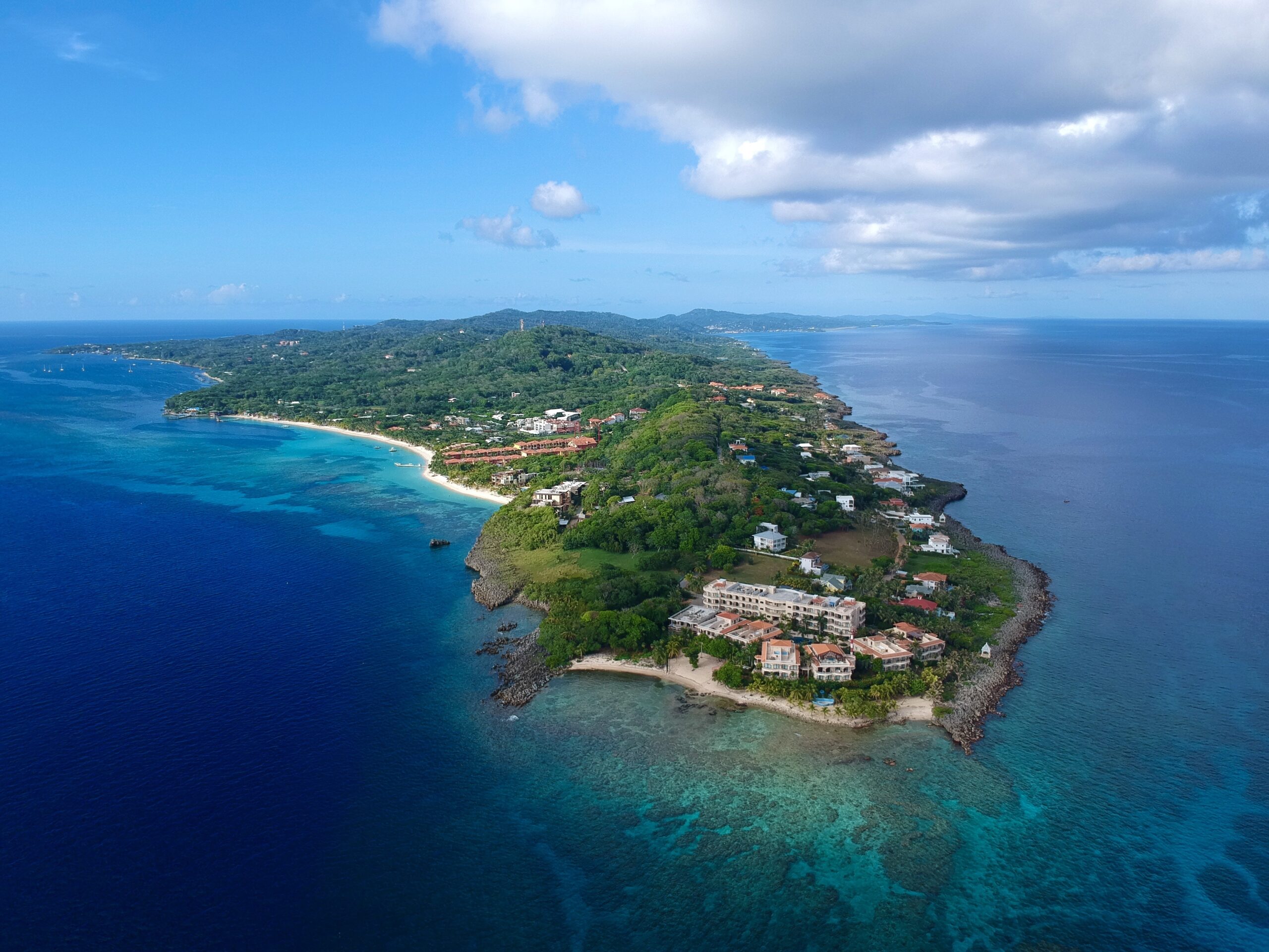 Aerial view of Roatán in the Bay Islands, Honduras, showing crystal-clear turquoise waters and lush green coastline