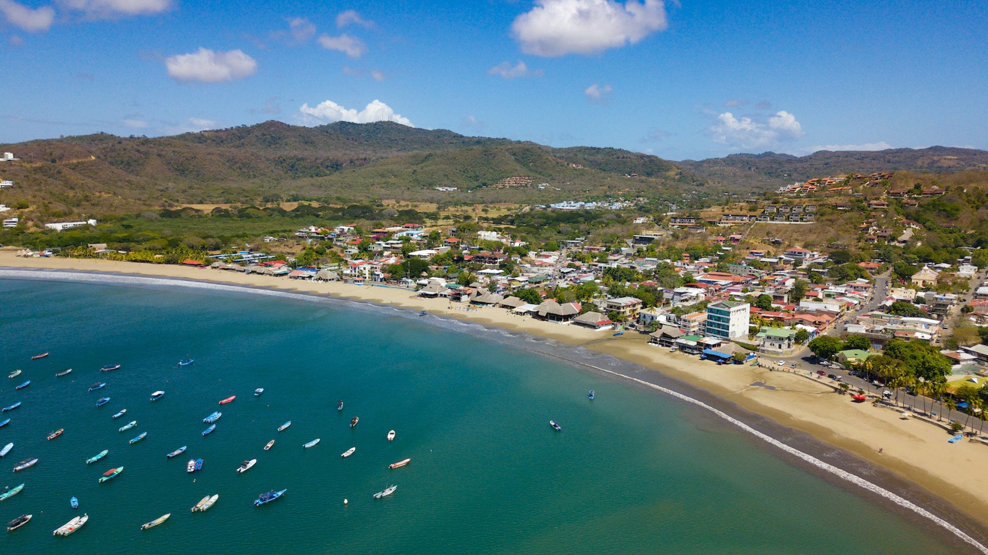 Panoramic view of San Juan del Sur bay in Nicaragua showing the horseshoe-shaped beach and colorful town