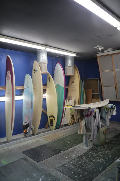 Multiple surfboard blanks lined up in a shaping room ready for finishing