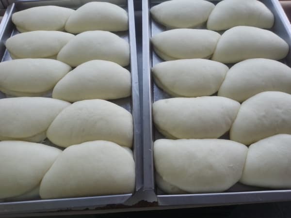 Panes bao armados en bandejas de producción, antes de la cocción al vapor