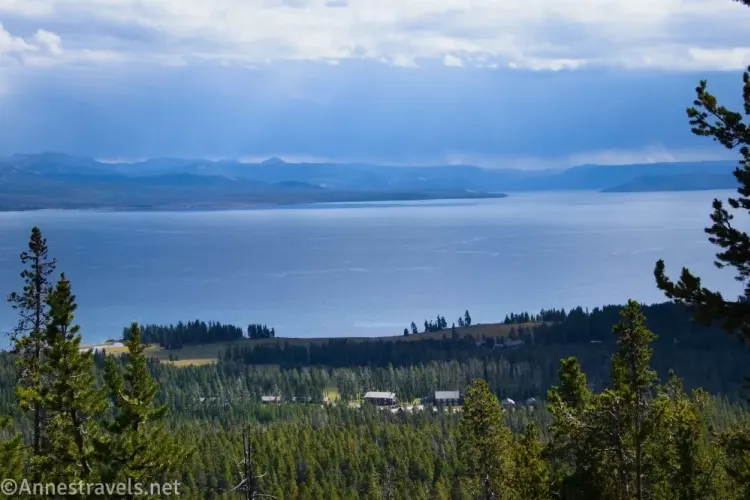 Gloomy clouds over mountains and a lake and forest surrounding buildings